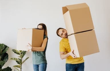 man and woman carrying moving boxes