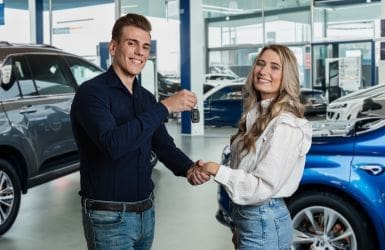 vrouw krijgt sleutel van nieuwe auto in showroom