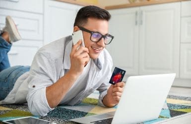 man lying down with laptop and credit card