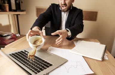 a cup of coffee falls on a laptop