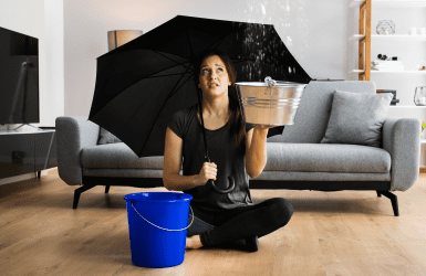vrouw met paraplu vangt water in emmer op