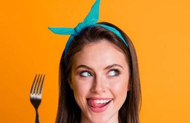 woman with fork licks her lips