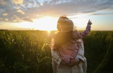 Child on back parent grain field