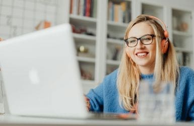 vrouw met koptelefoon achter laptop