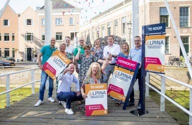 Groep mensen die juichen met een makelaarsbord